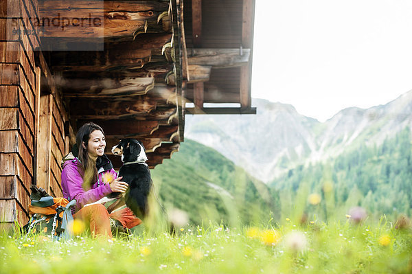 Österreich  Altenmarkt-Zauchensee  junge Frau und Hund vor einer Alpinhütte