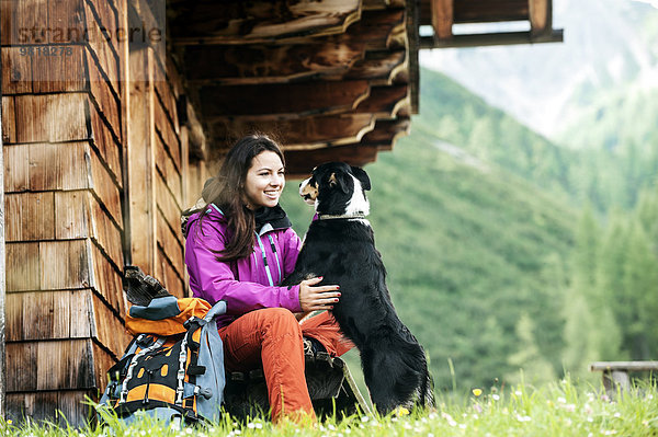 Österreich  Altenmarkt-Zauchensee  junge Frau und Hund vor einer Alpinhütte