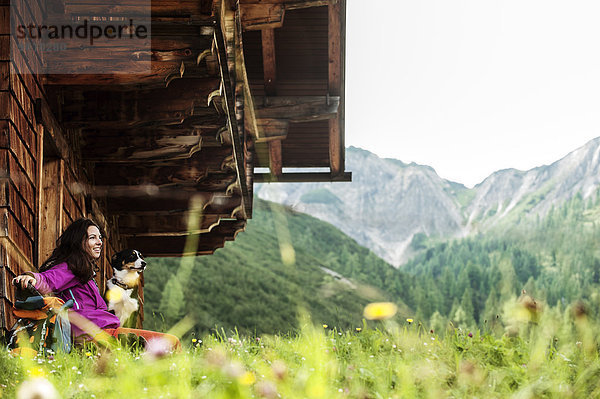 Österreich  Altenmarkt-Zauchensee  junge Frau und Hund vor einer Alpinhütte