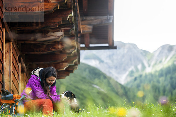 Österreich  Altenmarkt-Zauchensee  junge Frau und Hund vor einer Alpinhütte