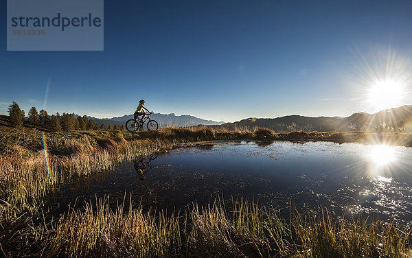 Österreich  Altenmarkt-Zauchensee  junge Frau auf dem Mountainbike bei Sonnenaufgang