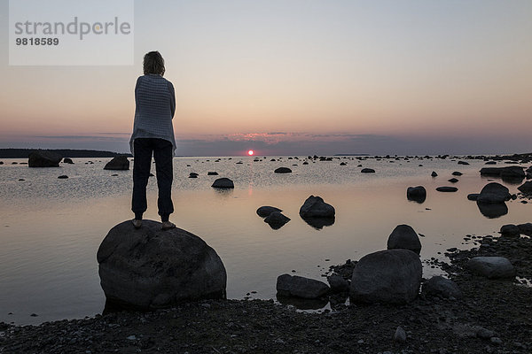 Estland  Kaesmu  Frau auf einem Felsen stehend  Sonnenuntergang beobachtend