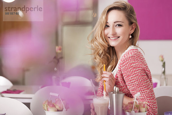 Porträt einer entspannten blonden Frau im Café mit Latte Macciato