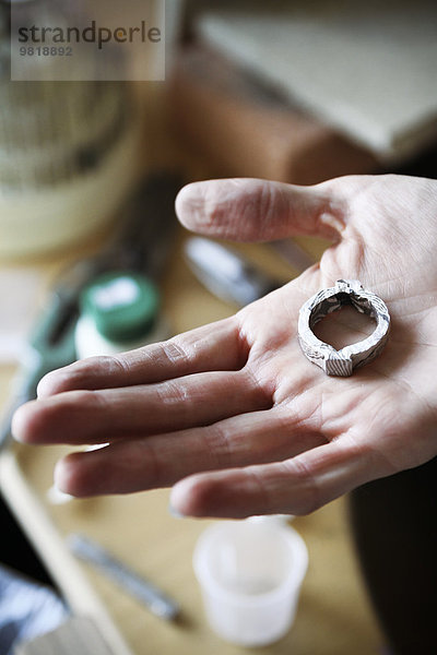 Goldschmiedin arbeitet an Eheringen im Mokume Gane Stil  Hand hält unfertigen Ring