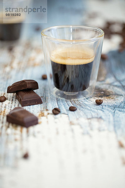 Glas Tasse Espresso  geröstete Kaffeebohnen und dunkle Schokolade auf Holz
