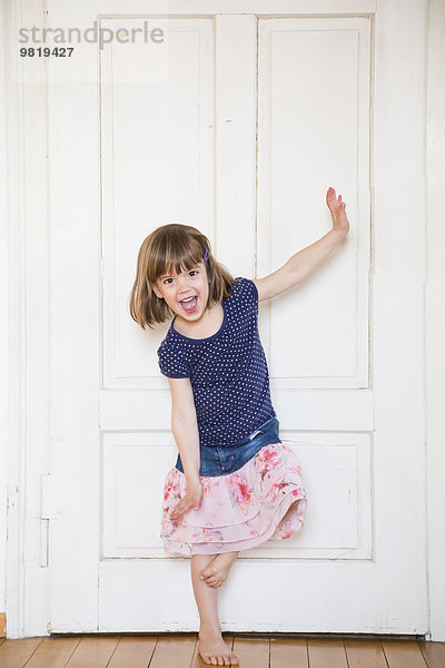 Fröhliches Mädchen tanzt an der Holztür