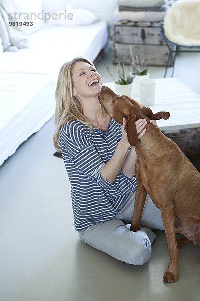 Frau spielt mit ihrem Hund zu Hause