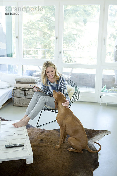 Frau mit Hund und digitalem Tablett zu Hause