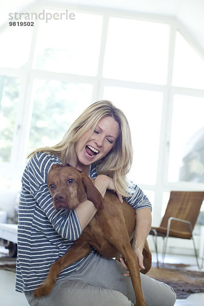 Frau spielt mit ihrem Hund zu Hause