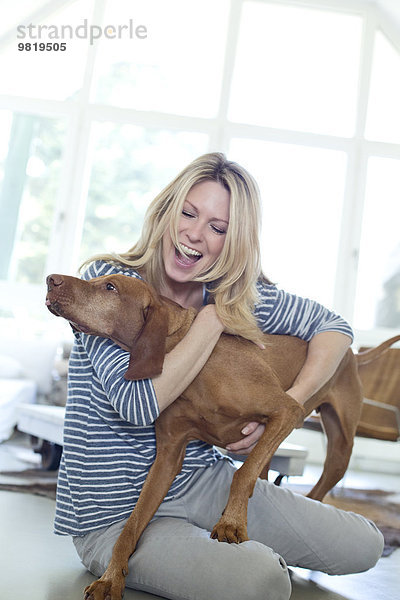 Frau spielt mit ihrem Hund zu Hause