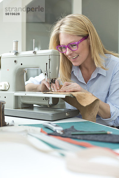 Lächelnde Frau bei der Arbeit an der Nähmaschine