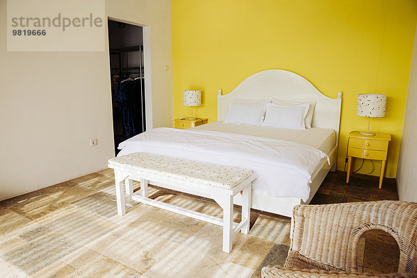 Indonesien  Bali  Schlafzimmer mit gelber Wand und gelben Nachttischen einer Ferienvilla