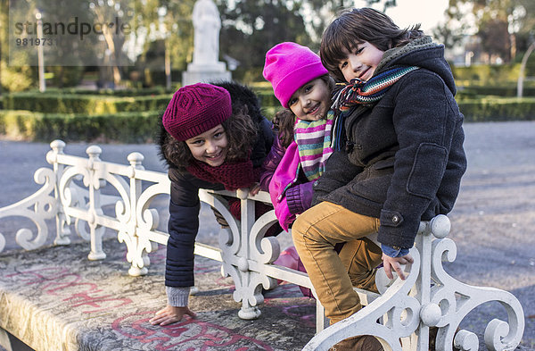 Spanien  Gijon  drei lächelnde Kinder Seite an Seite in einem Park an einem Wintertag