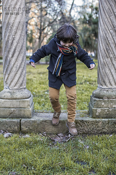 Kleiner Junge  der sich an einem Wintertag im Park amüsiert.