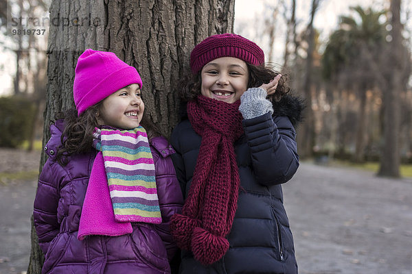 Zwei lächelnde kleine Mädchen im Park an einem Wintertag