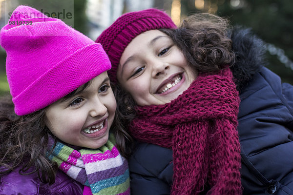 Porträt von zwei glücklichen kleinen Mädchen in einem Park an einem Wintertag