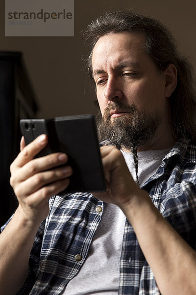 Mann mit geflochtenem Bart auf dem Smartphone