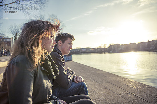 Deutschland  Berlin  Teenagerpaar am Seeufer am späten Nachmittag