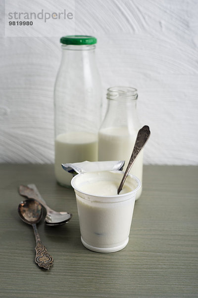 Milchflaschen und Tasse Naturjoghurt