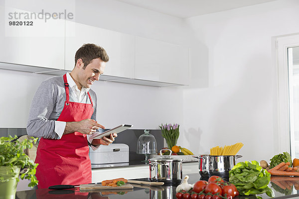 Lächelnder Mann beim Betrachten des digitalen Tabletts in der Küche
