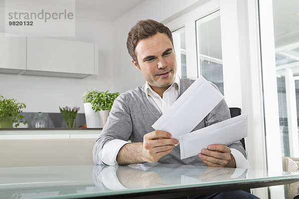 Mann in der Küche sitzend mit Buchstaben