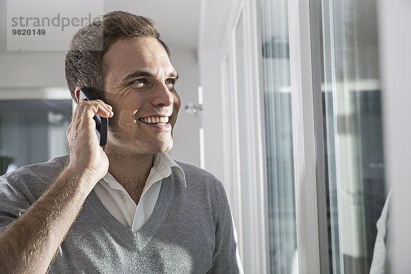 Porträt eines lächelnden Mannes beim Telefonieren mit dem Smartphone