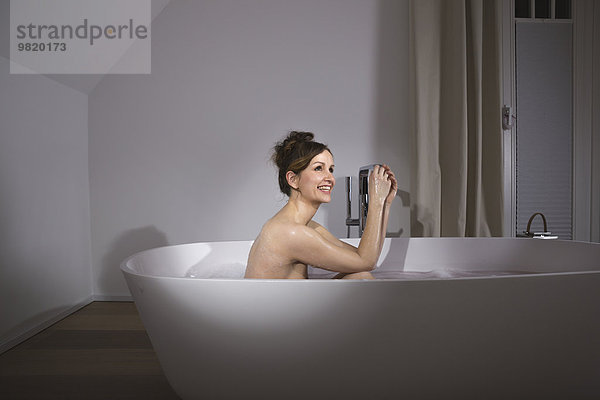 Lächelnde Frau entspannt in moderner Badewanne