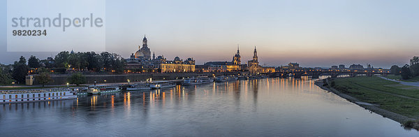 Deutschland  Dresden  Blick auf die beleuchtete Stadt mit der Elbe im Vordergrund am Abend