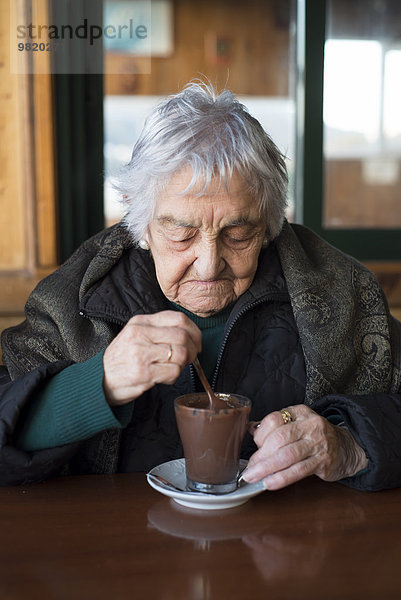 Alte Frau trinkt eine heiße Schokolade