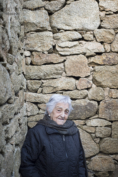 Spanien  Galizien  Ferrol  alte Frau an der Steinmauer