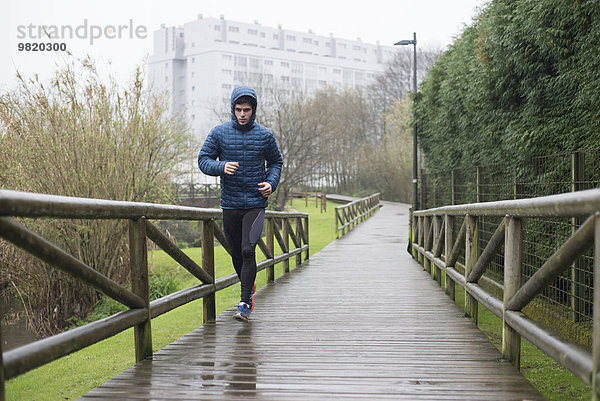 Spanien  Galizien  Naron  Läufer auf einer Promenade im Park an einem regnerischen Tag