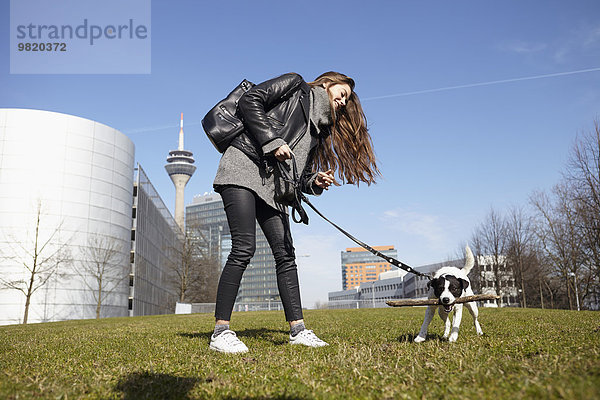Deutschland  Düsseldorf  Junge Frau spielt mit ihrem Hund