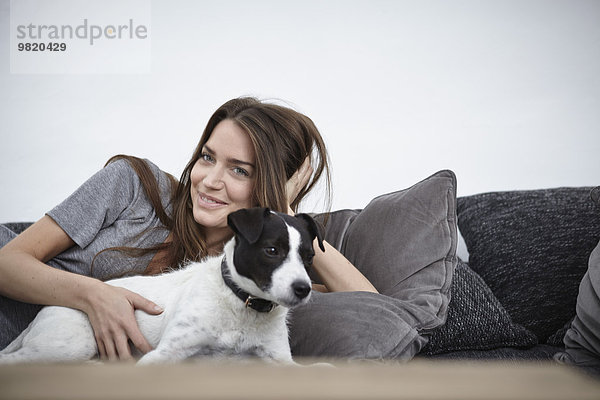 Junge Frau entspannt mit Hund auf der Couch
