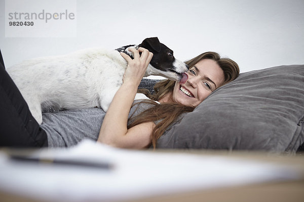 Junge Frau spielt mit Hund auf der Couch