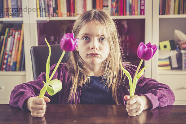 Porträt eines schmollenden Mädchens mit zwei Tulpen in der Hand