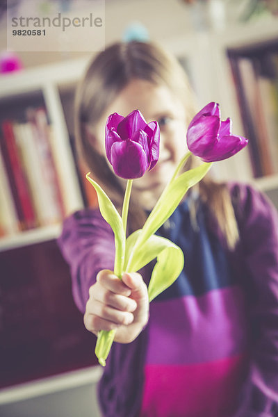 Kleines Mädchen mit zwei violetten Tulpen