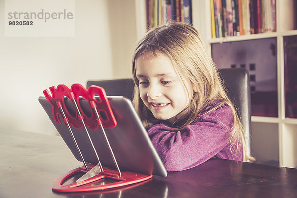 Lächelndes kleines Mädchen mit digitalem Tablett