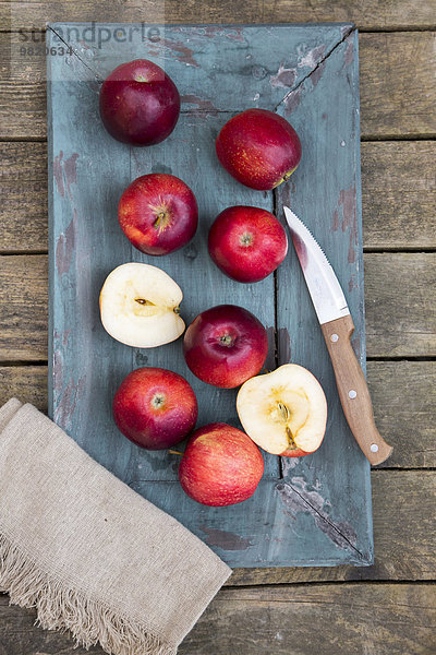Rote Äpfel  Messer und Platzdeckchen auf dunklem Holz