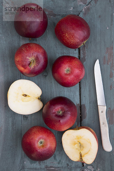 Rote Äpfel und Messer auf dunklem Holz