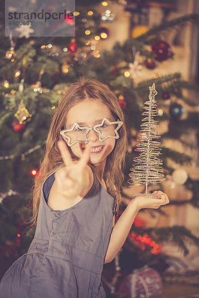 Porträt eines glücklichen kleinen Mädchens vor dem Weihnachtsbaum