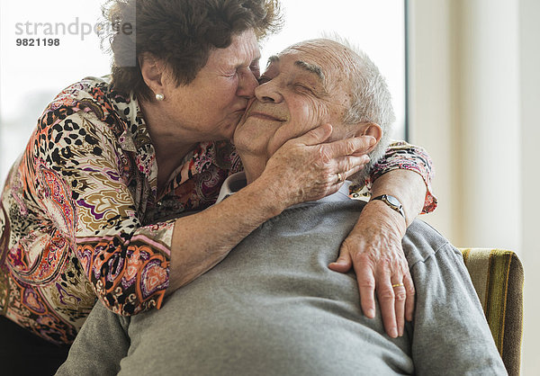 Seniorin  die seinen Mann umarmt und küsst.