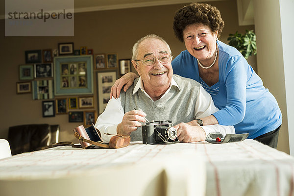 Glückliches Seniorenpaar mit alter Kamera zu Hause