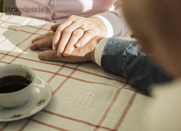 Seniorenpaar hält in der Kaffeepause Händchen