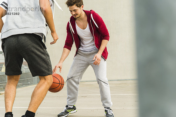Zwei junge Männer spielen Basketball auf Parkebene