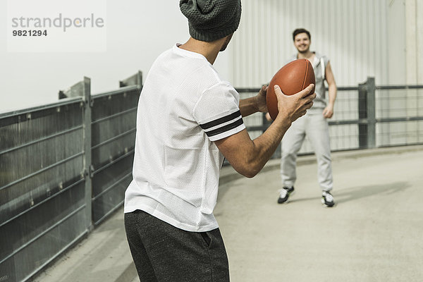 Zwei junge Männer spielen mit Fußball auf der Straße