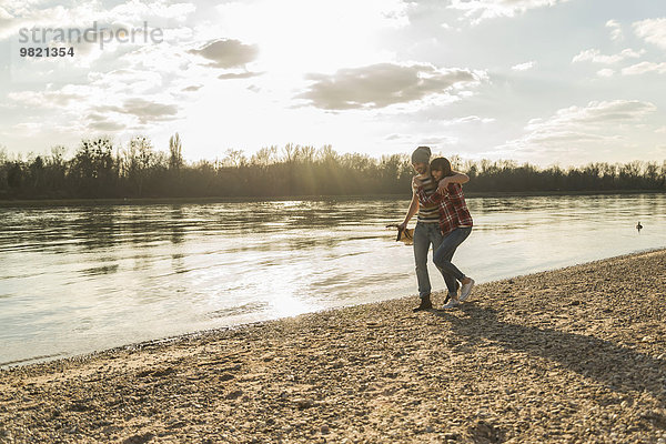 Glückliches junges Paar  das am Flussufer spazieren geht