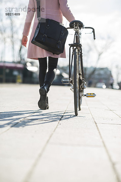 Junge Frau mit Fahrrad in der Stadt