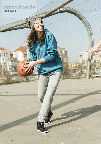 Junge Frau spielt Basketball