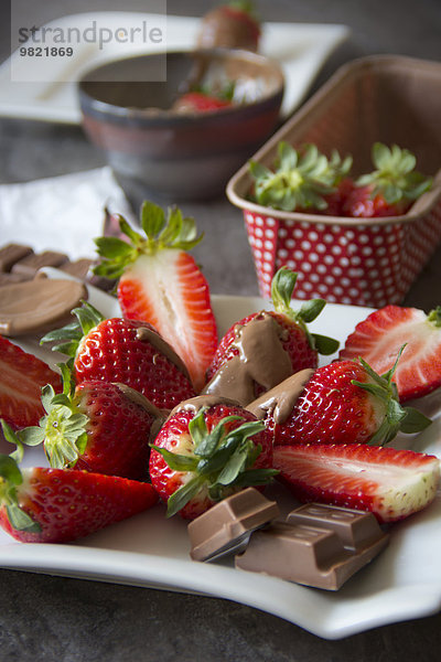 Teller mit geschnittenen Erdbeeren umhüllt von Schokolade
