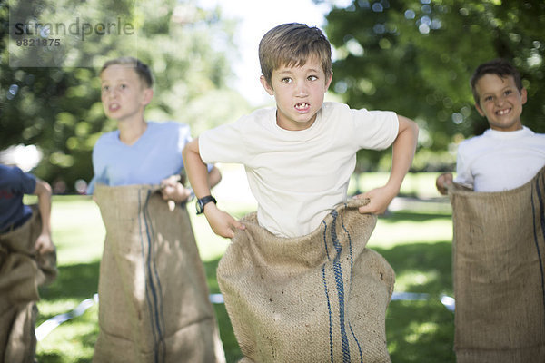 Jungen  die an einem Sackhüpfen teilnehmen.